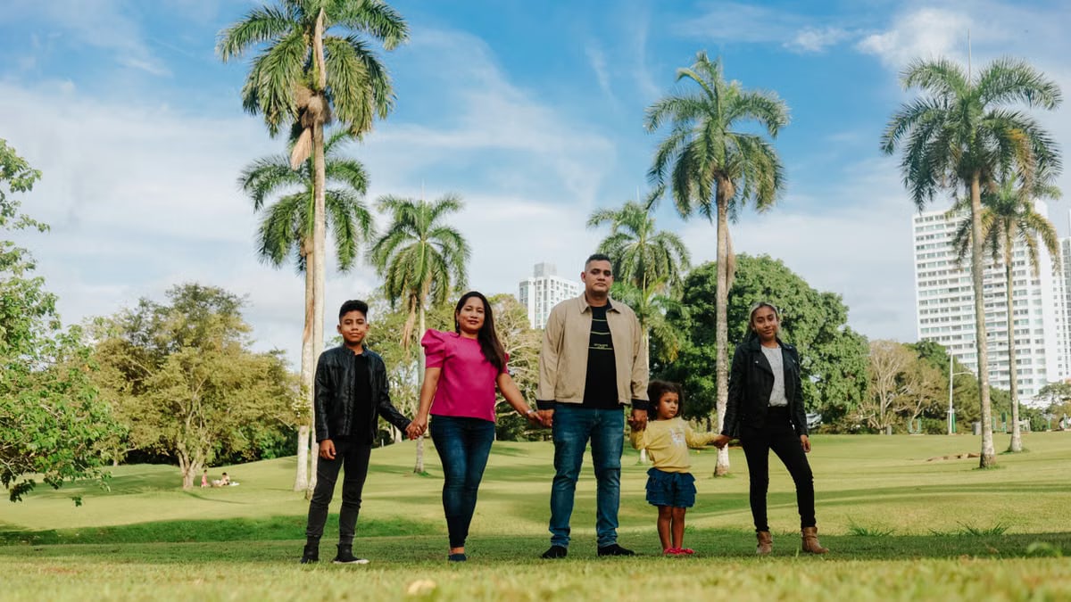 A cheerful family enjoys a sunny day in the park, surrounded by palm trees and lush greenery.