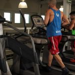 Two men running on treadmills in a modern gym, promoting fitness and health.